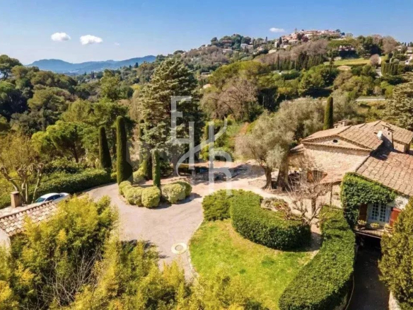Mas provençal en pierre avec vue panoramique à Mougins, entouré de verdure.