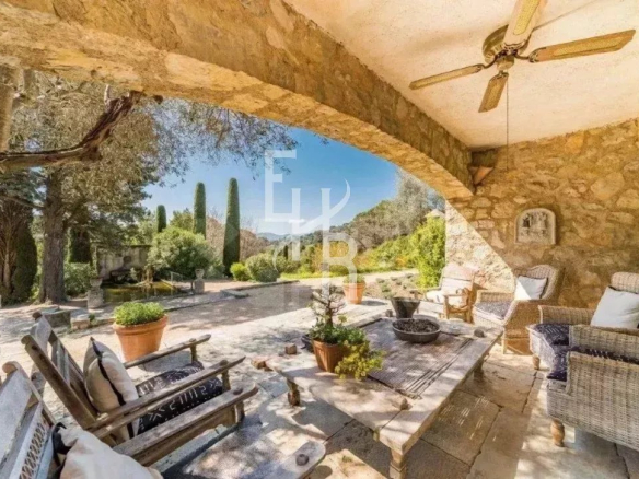 Terrasse en pierre d'une maison provençale à Mougins, avec mobilier extérieur et vue sur le jardin.