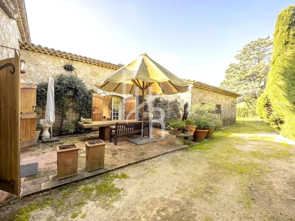 Terrasse d'une maison en pierre à Mougins avec parasol et mobilier extérieur