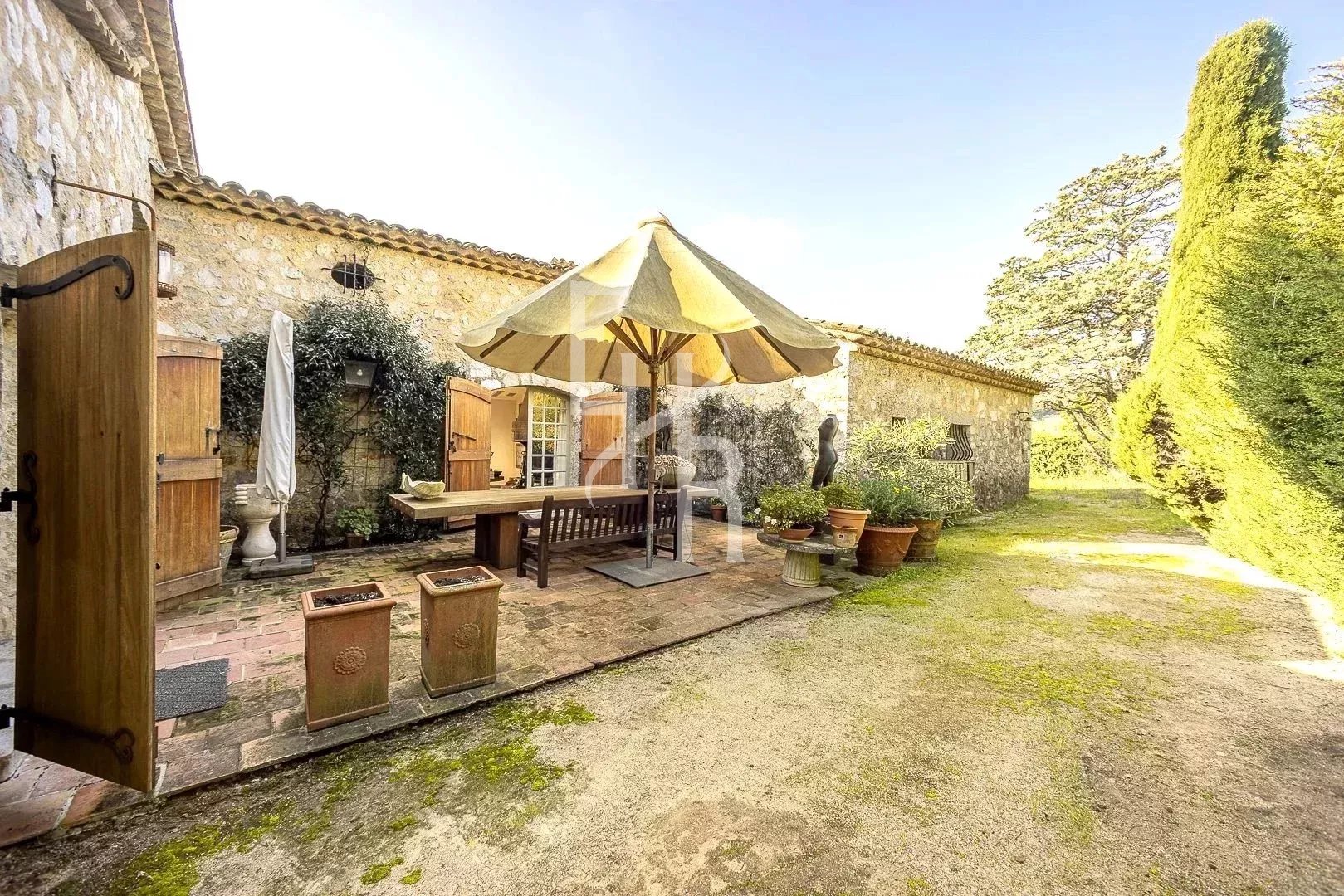 Terrasse d’une propriété provençale à Mougins Terrasse d'une maison en pierre à Mougins avec parasol et mobilier extérieur
