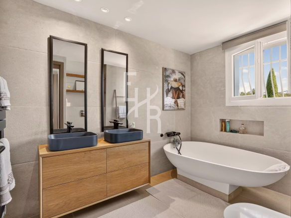 Modern bathroom with double sink and bathtub, grey stone walls.