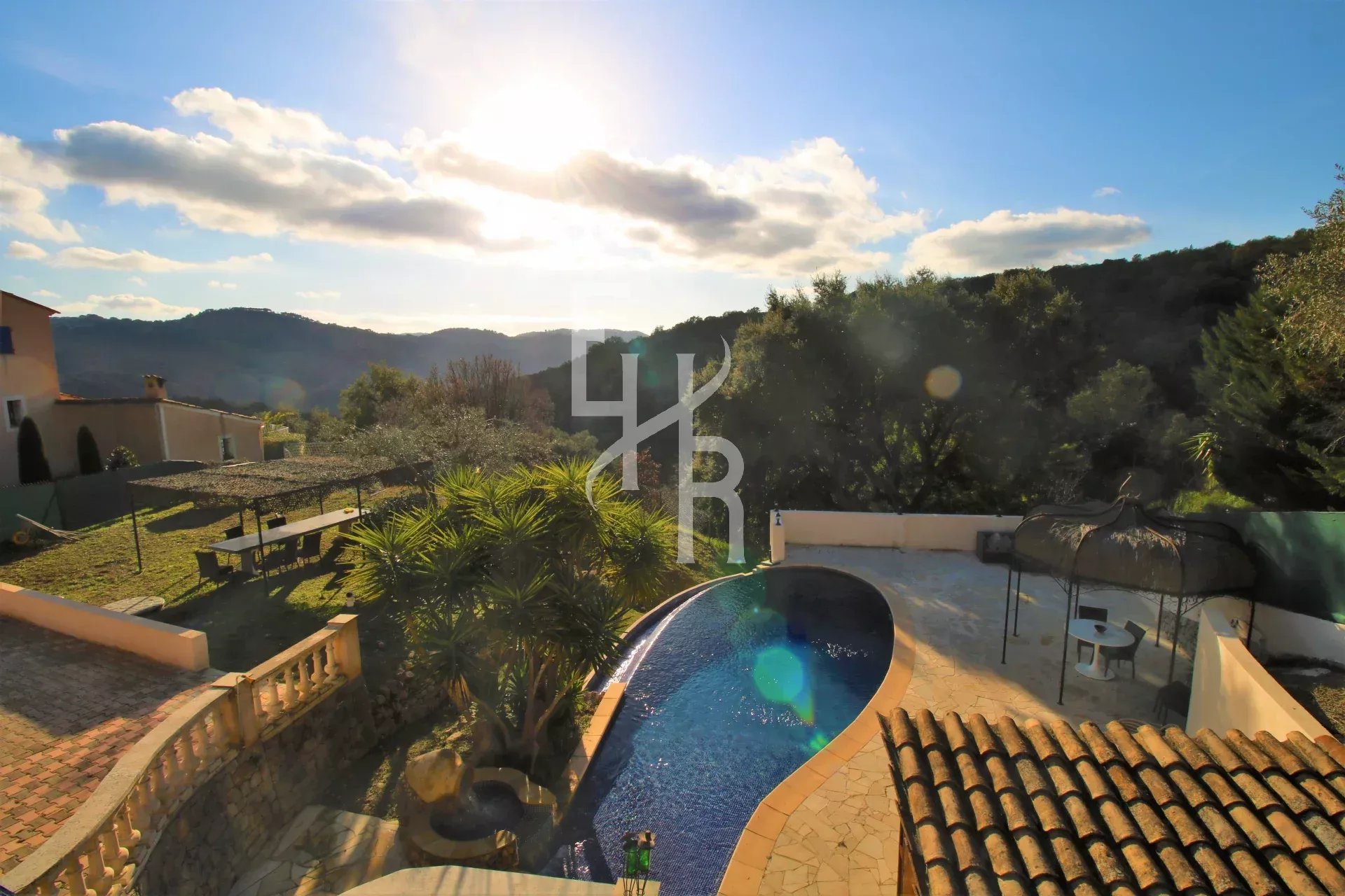 Vue d'une villa avec piscine et paysage montagneux à Peymeinade sous un ciel ensoleillé.