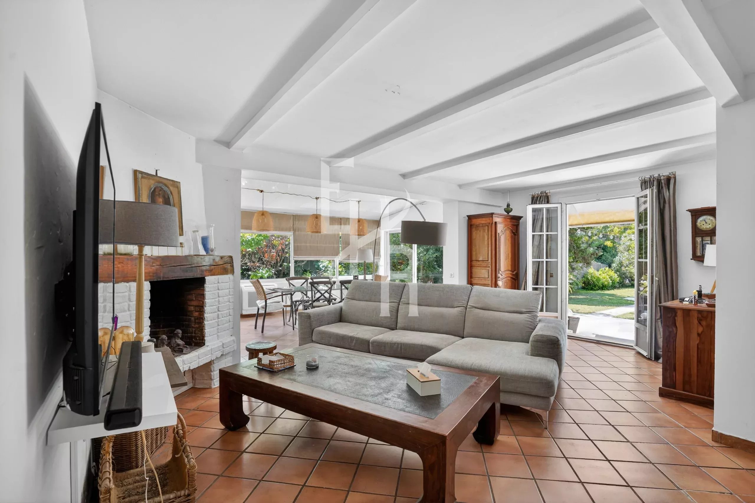 Salon d’une villa à Mougins Intérieur d'une villa avec un salon spacieux, canapé et cheminée, donnant sur un jardin.
