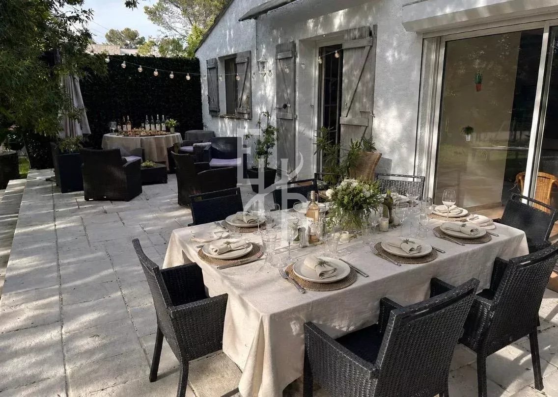 Terrasse d’une villa à Mougins Terrasse d'une villa avec une table dressée pour un repas en extérieur, chaises noires et décor floral.