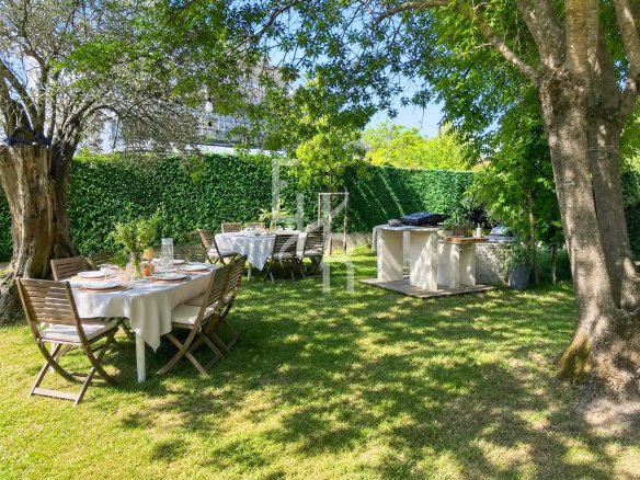 Jardin d'une villa avec tables en bois et barbecue, entouré d'arbres à Mougins.