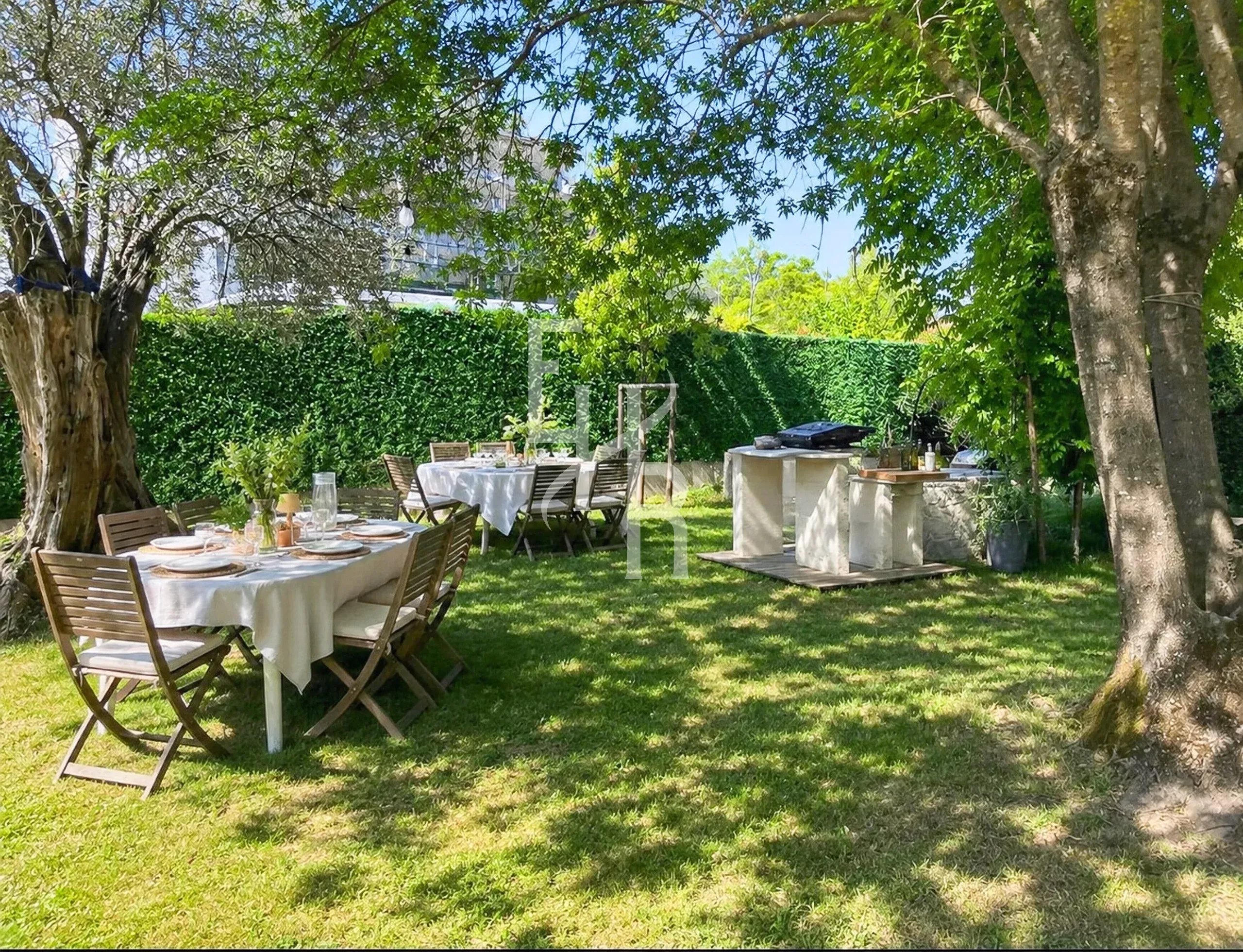 Jardin de villa à Mougins Jardin d'une villa avec tables en bois et barbecue, entouré d'arbres à Mougins.