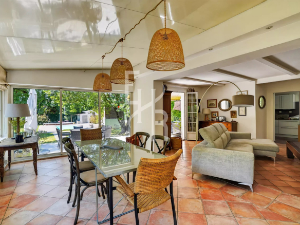 Intérieur d'une villa avec salle à manger et salon lumineux, fenêtres donnant sur le jardin.