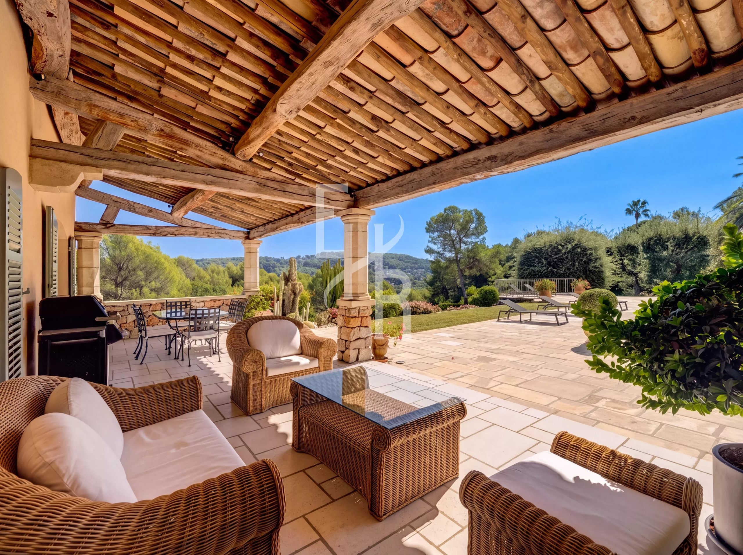 Terrasse d’une villa à Mougins Terrasse ensoleillée avec mobilier en osier et vue sur le jardin verdoyant d'une villa à Mougins.