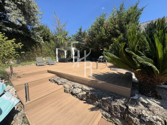 Terrasse en bois avec transats et espace jardin dans une villa à Mougins.