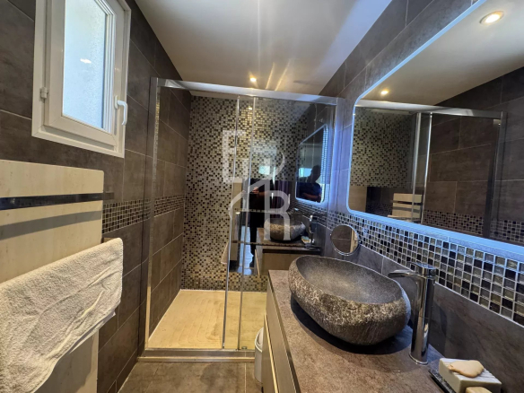 Salle de bains moderne avec douche à l'italienne et lavabo en pierre.