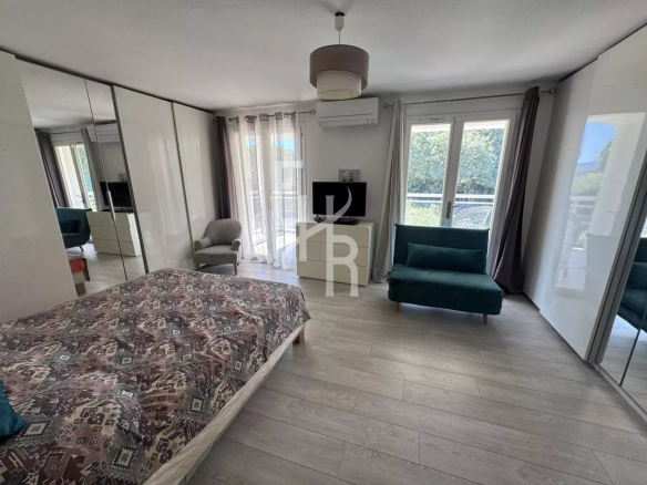 Chambre spacieuse avec lit, télévision et accès à un balcon dans une villa à Mougins.