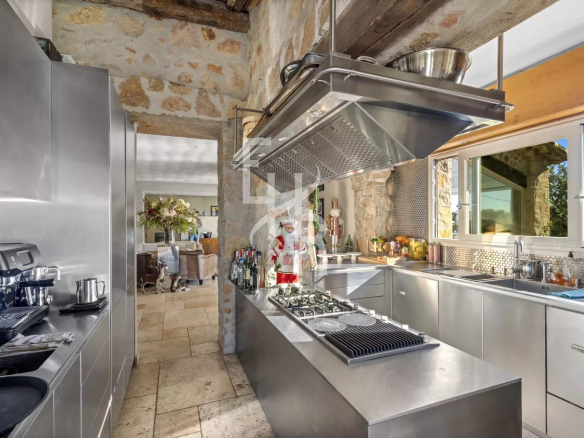 Modern kitchen in a Provençal villa in Mougins, with stainless steel elements and a view of the living room.