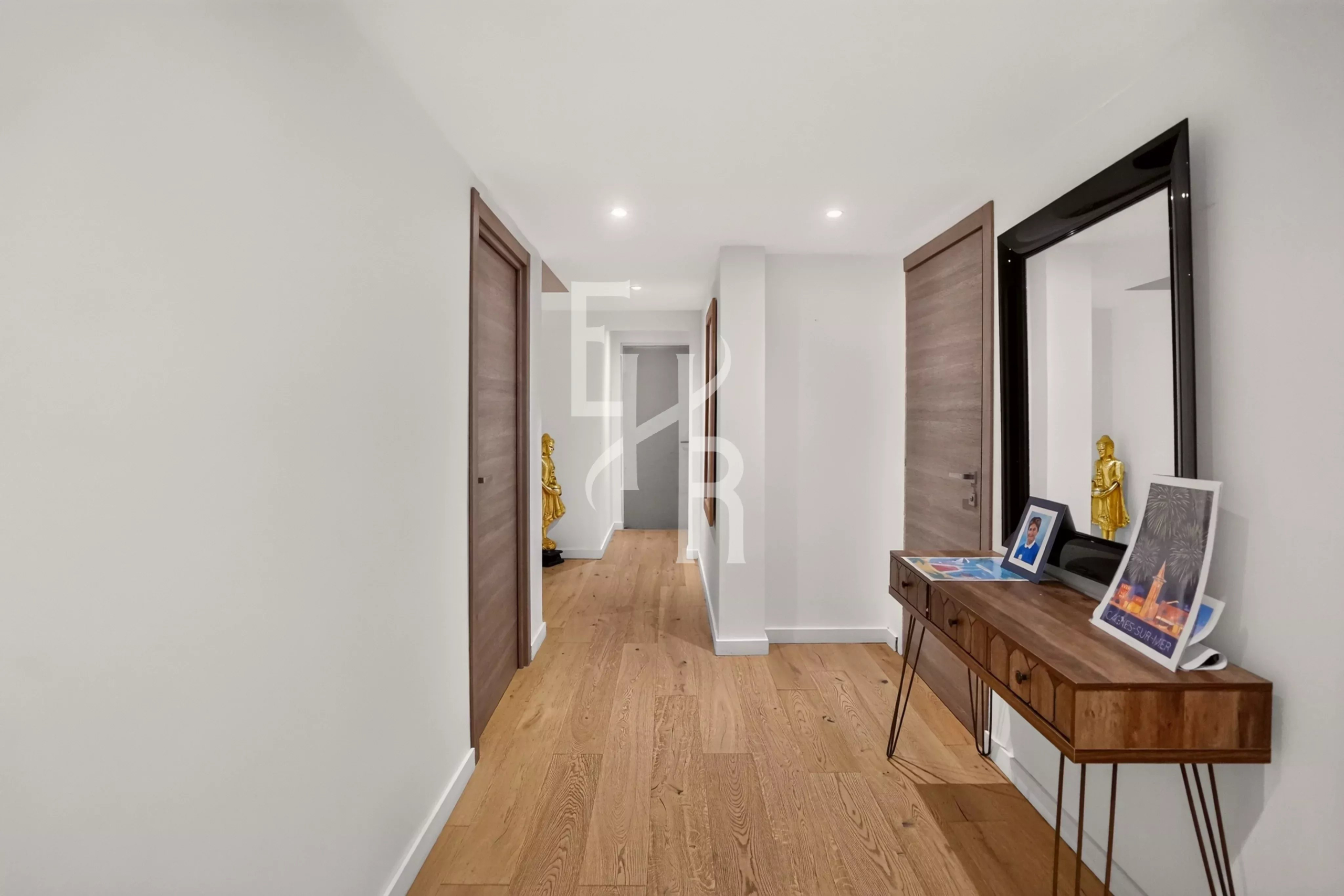 Couloir lumineux d'une villa moderne avec parquet en bois et portes en bois, à Mougins.