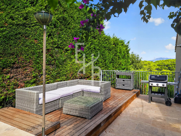 Terrasse en bois avec mobilier de jardin et barbecue, entourée de verdure à Mougins.