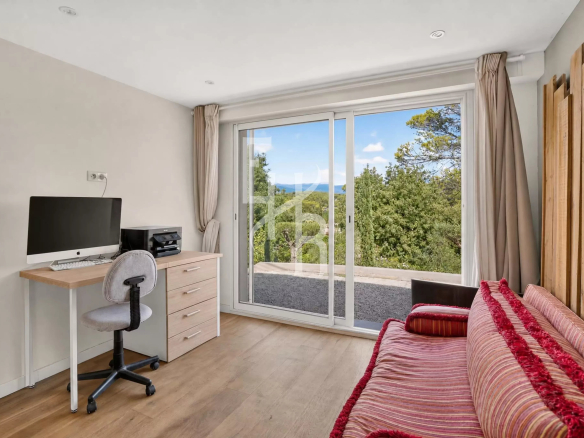 Intérieur d'une villa à Mougins avec bureau, canapé et vue sur la nature.