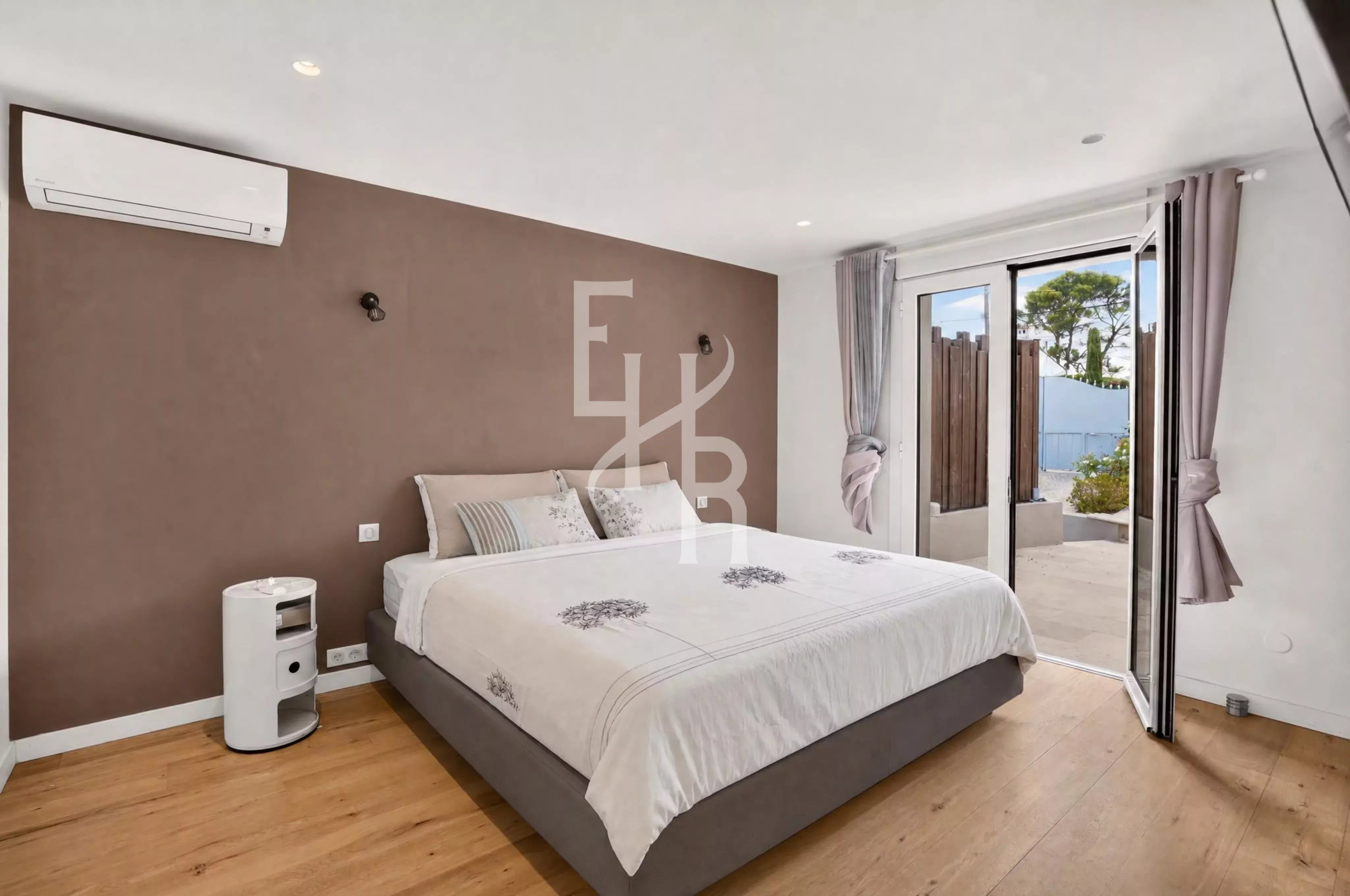 Chambre d'une villa moderne avec lit double et accès à une terrasse extérieure à Mougins.