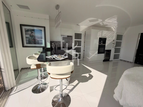 Interior of a modern apartment with open kitchen and dining area, abundant natural light.