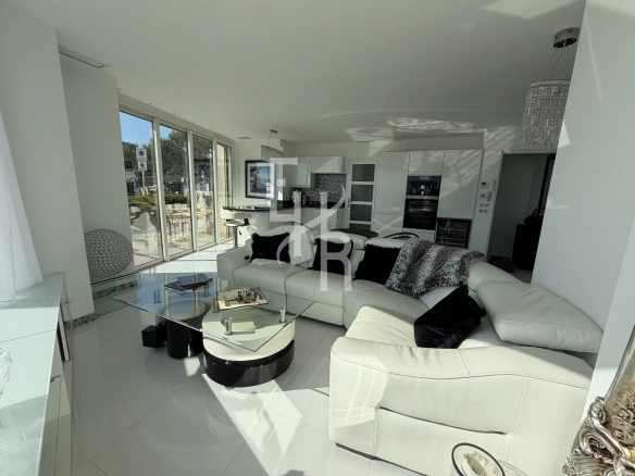 Interior of a modern apartment with a bright living room and large windows overlooking the sea.