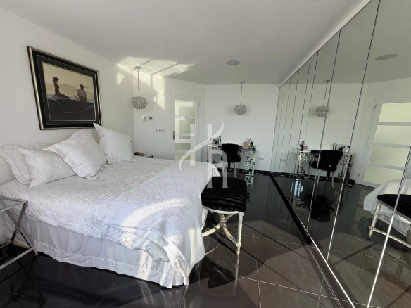 Bedroom in a modern apartment with a double bed and mirror, elegantly decorated.