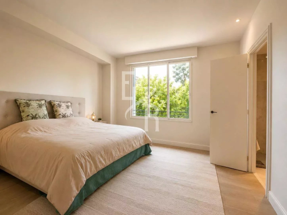 Spacious room with double bed and window overlooking a garden.