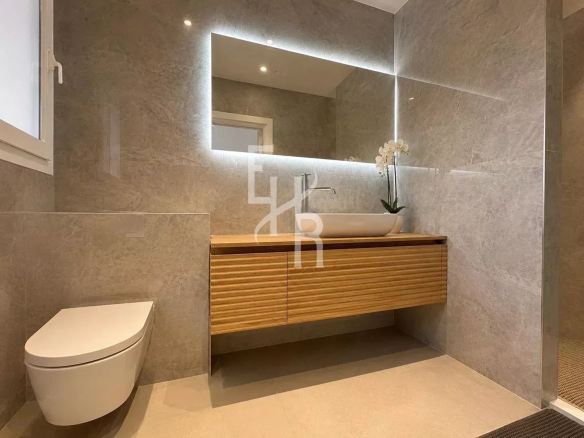 Modern bathroom with wooden vanity and sink, grey stone tiles.