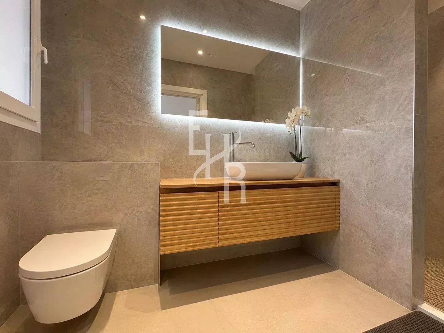 Modern bathroom with wooden vanity and sink, grey stone tiles.