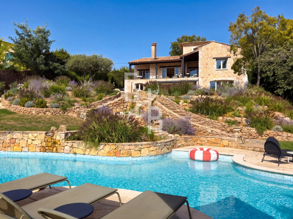 Stone country house with swimming pool and garden in Mougins, surrounded by vegetation.