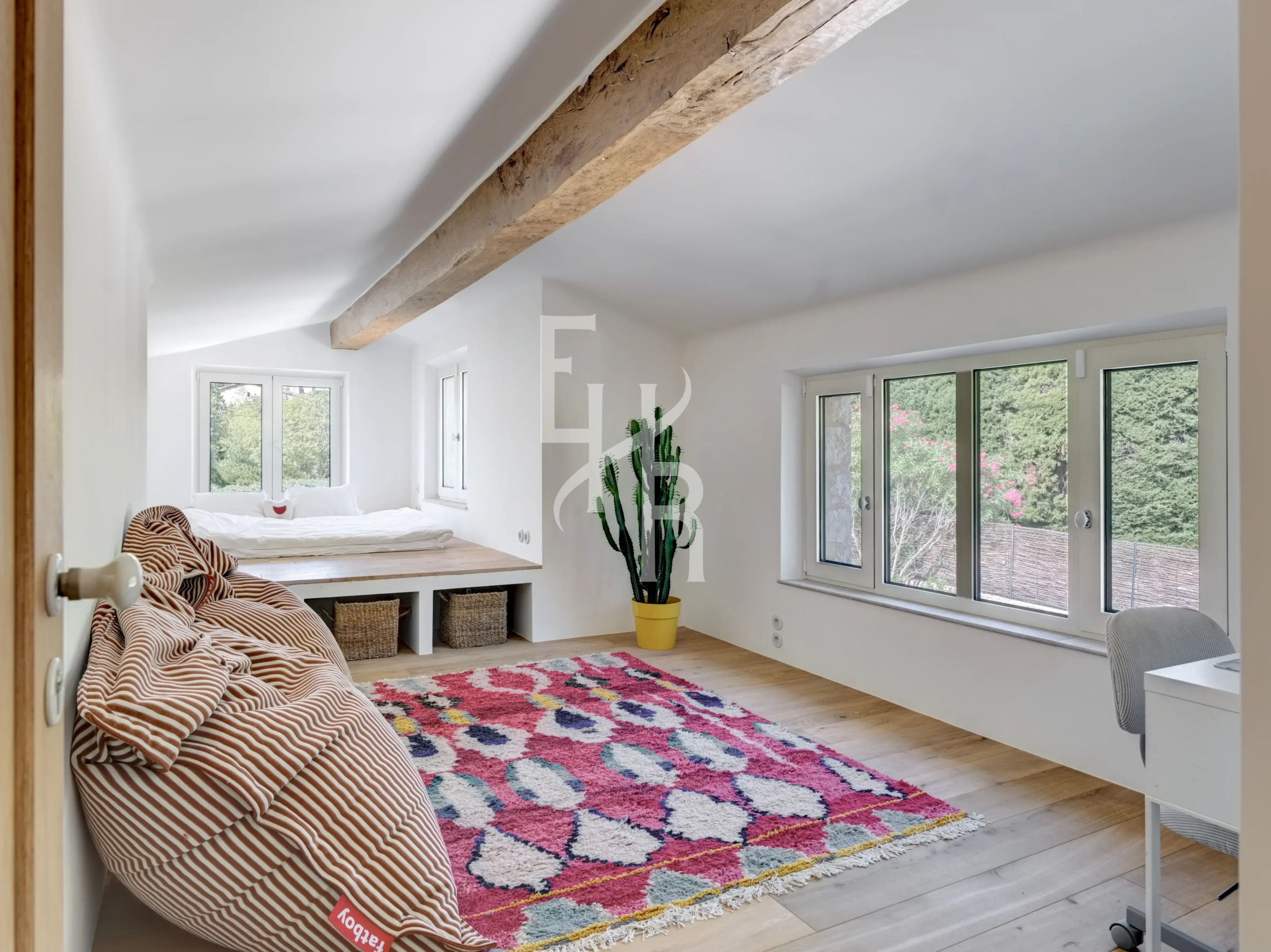 Modern room in Mougins Interior of a bright bedroom with a colorful rug and a desk area.