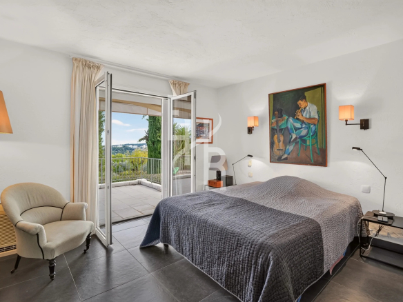 Chambre d'une villa à Mougins avec vue panoramique, lit double et accès à une terrasse.