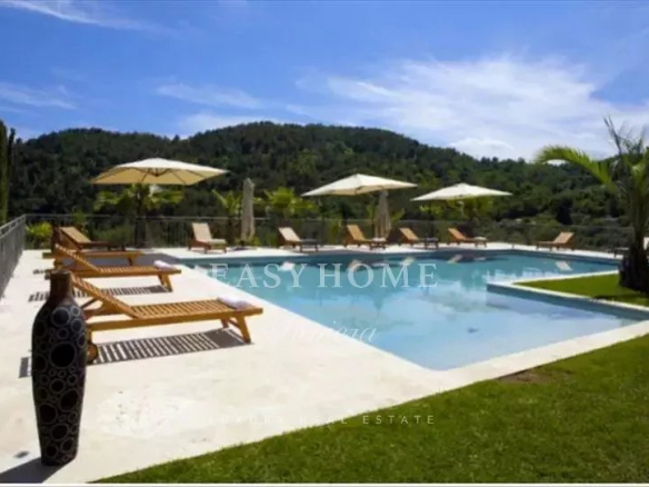 View of a swimming pool surrounded by sun loungers and parasols in a villa estate in Grasse.