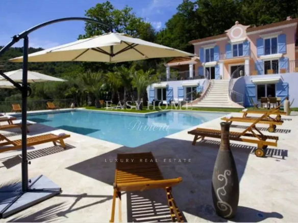View of a swimming pool surrounded by sun loungers and parasols in a villa estate in Grasse.