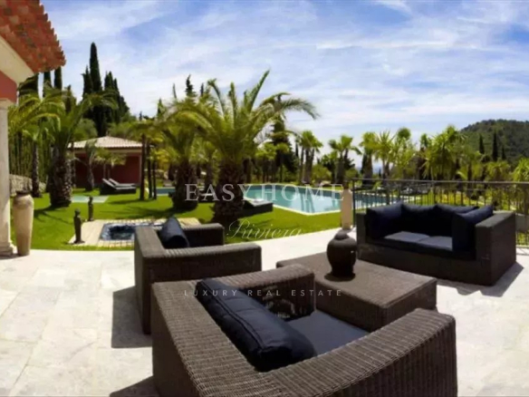 Terrace of a luxury villa in Grasse with wicker furniture and view of the pool and garden.
