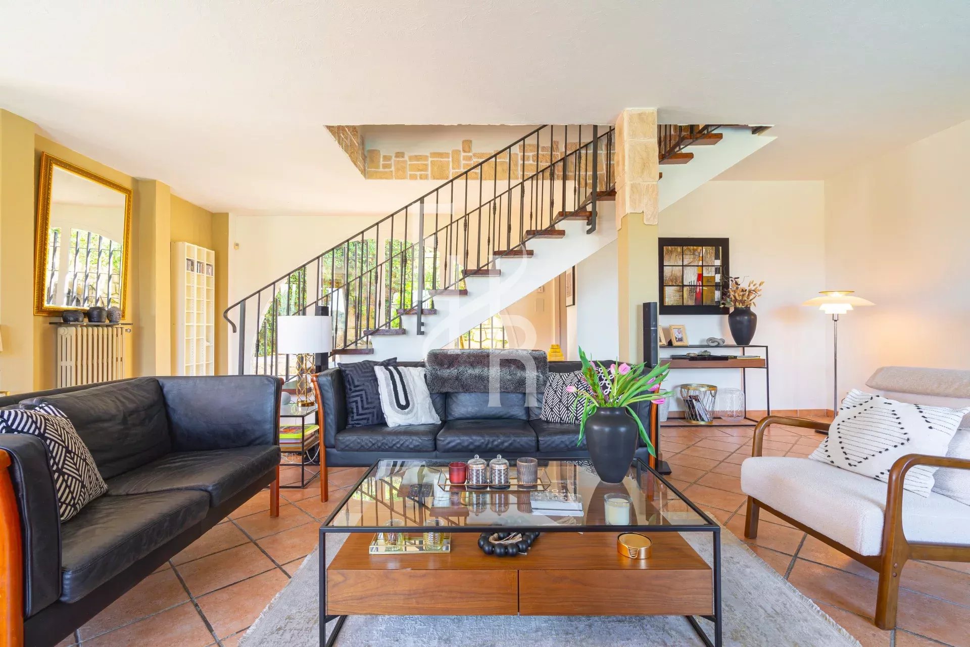 Intérieur d'une villa à Vence avec un grand séjour lumineux et un escalier en colimaçon.