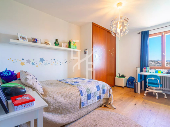 Chambre d'une villa à Vence avec vue sur les montagnes, décorée avec un lit et un bureau.