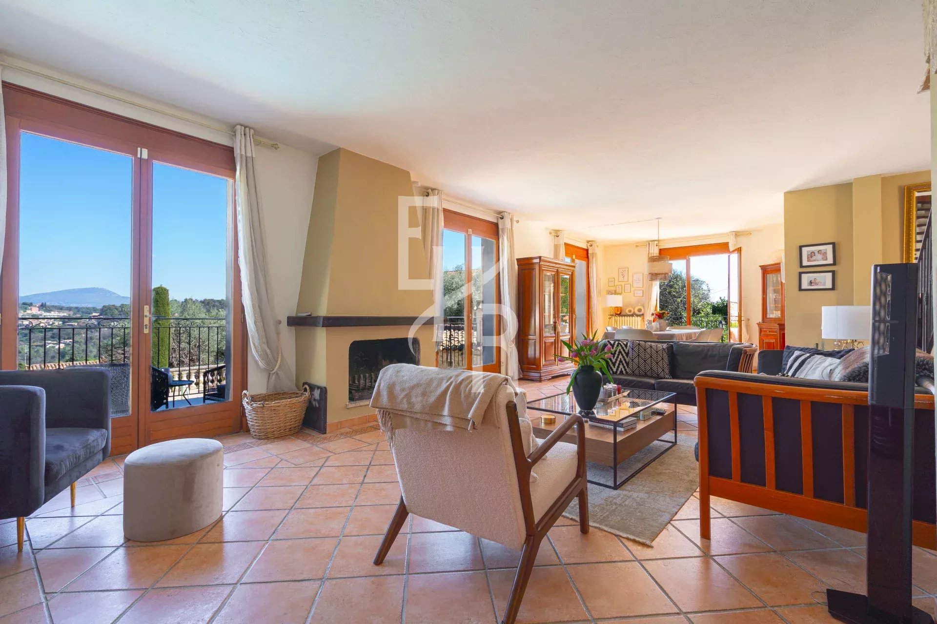 Intérieur lumineux d'une villa à Vence avec vue sur les montagnes, salon et salle à manger ouverts sur la terrasse.