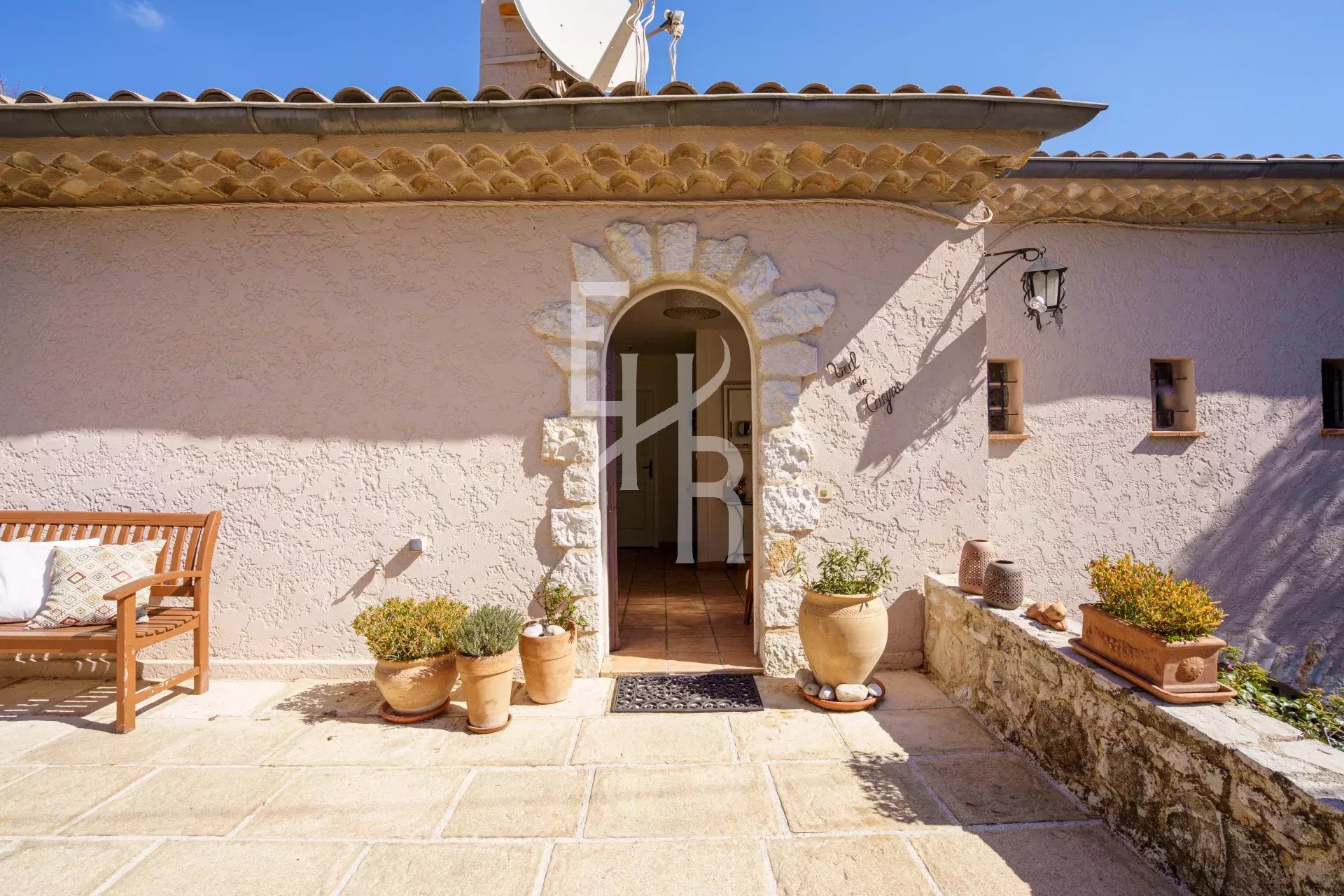 Entrée d'une villa à Vence avec un sol en pierre et des pots de fleurs.