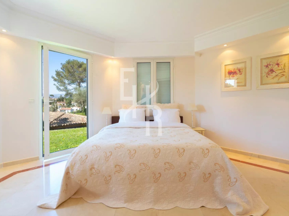 Chambre d'une villa à Mougins avec lit et vue sur l'extérieur.
