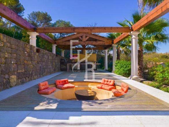 Terrasse avec un espace de détente et des fauteuils à Mougins, entourée de verdure.