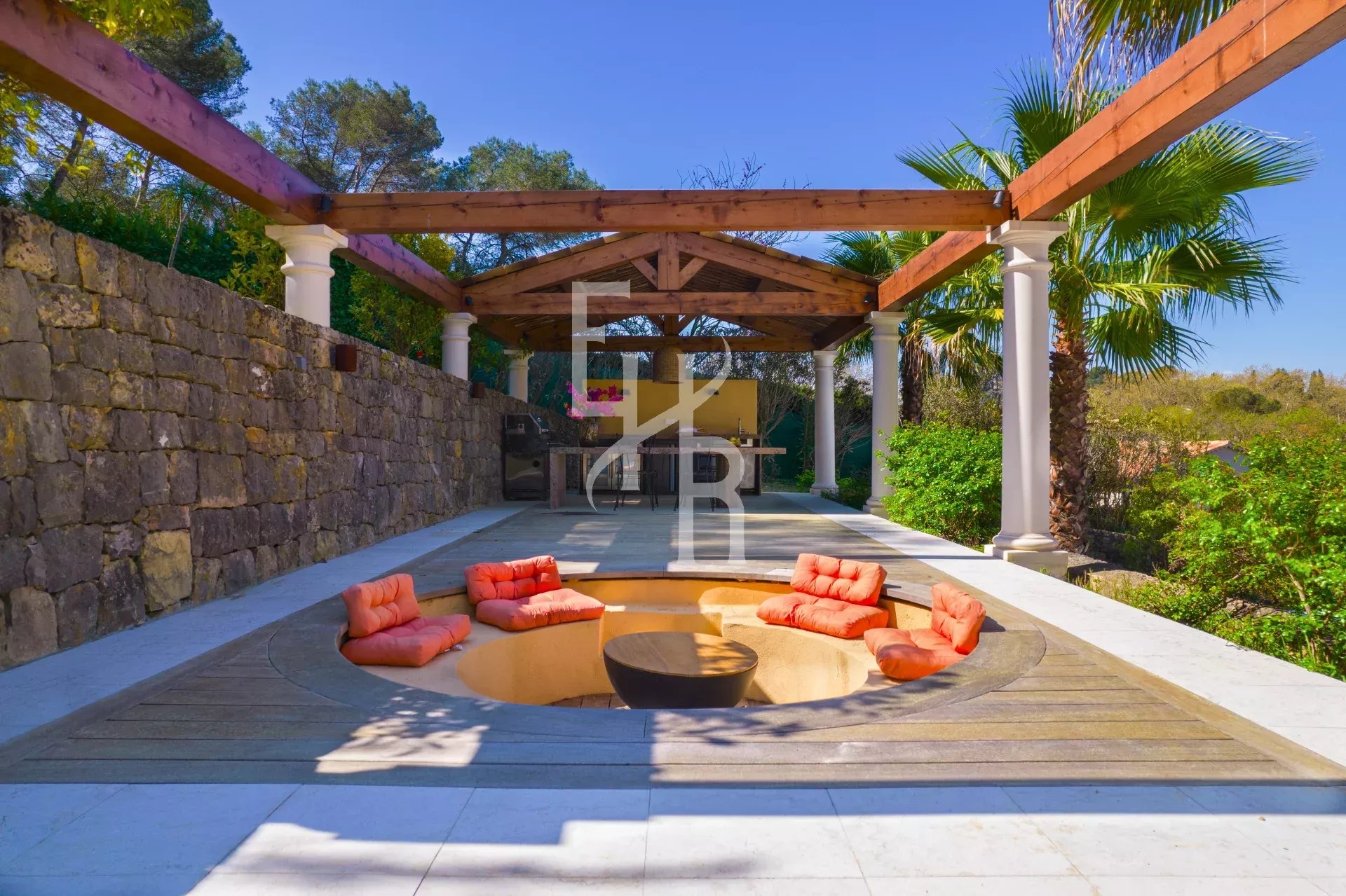 Terrasse avec un espace de détente et des fauteuils à Mougins, entourée de verdure.