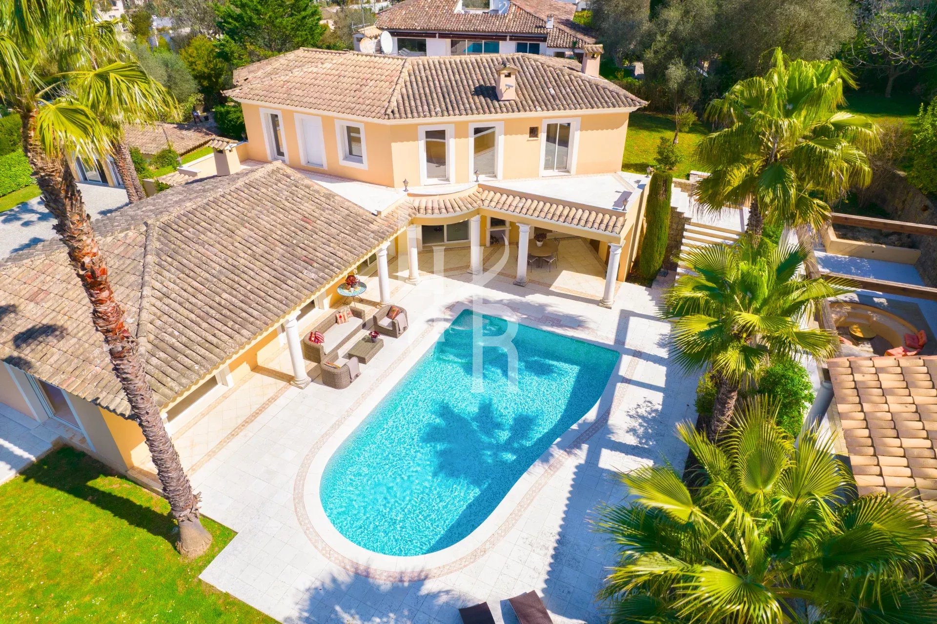 Vue aérienne d'une villa avec piscine à Mougins, entourée de palmiers et d'un jardin verdoyant.