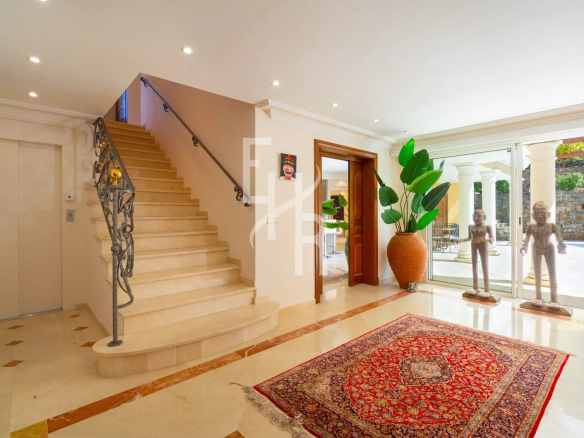Intérieur d'une villa à Mougins avec un escalier, des sculptures et un tapis au sol.