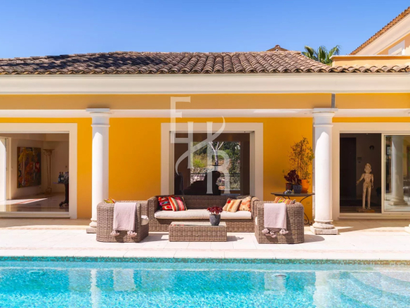 Villa avec piscine et mobilier de jardin à Mougins, murs jaunes et colonnes blanches.
