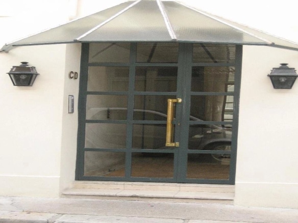 Entrée d'un immeuble en pierre de taille à Paris 16ème avec porte vitrée et lampadaires.