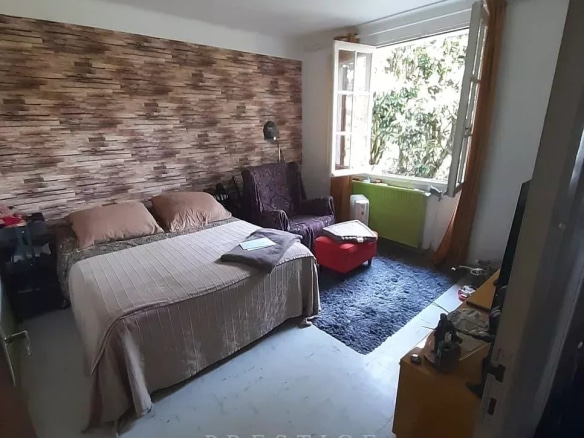Chambre d'une villa à Guérande avec lit, fauteuil et décoration en bois.