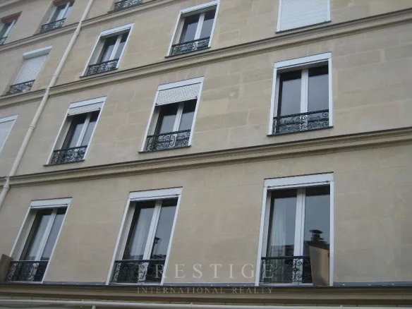 Façade d'un immeuble en pierre de taille à Paris 16ème avec fenêtres et balcons.