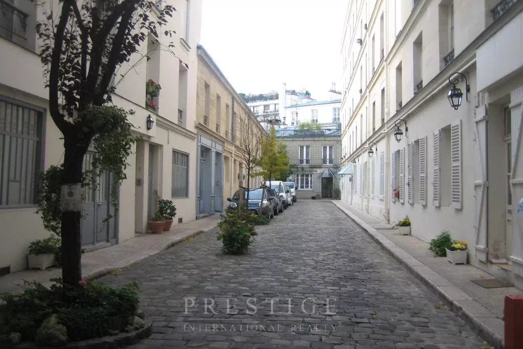 Rue tranquille à Paris 16ème Rue pavée à Paris 16ème avec des immeubles en pierre et des voitures garées.