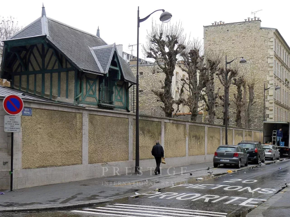 Rue à sens unique à Paris 16ème avec un immeuble en pierre de taille et des arbres taillés.
