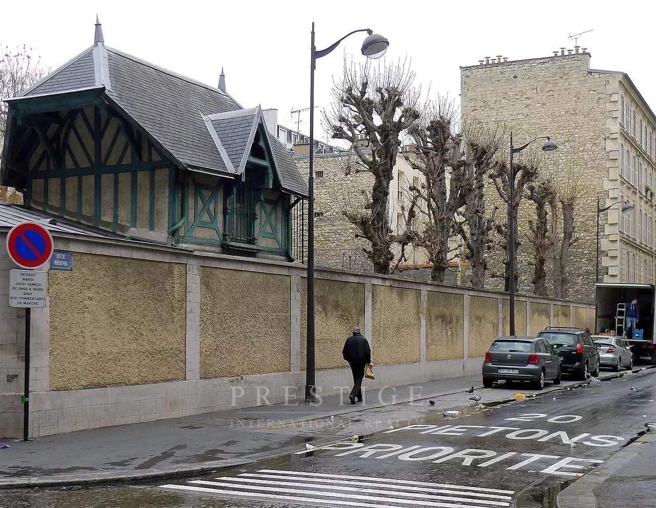 Rue à Paris 16ème Rue à sens unique à Paris 16ème avec un immeuble en pierre de taille et des arbres taillés.