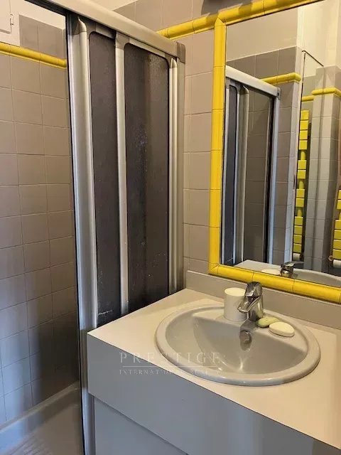 Salle de bain avec douche Salle de bain avec douche et lavabo, murs carrelés en gris, accessoires jaunes.