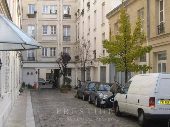 Rue calme avec immeubles en pierre de taille, voitures garées et arbres, Paris 16ème.